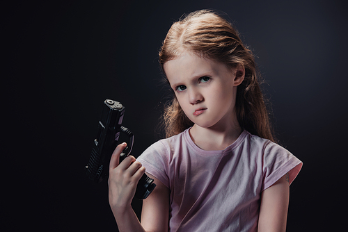 offended child holding gun and  isolated on black