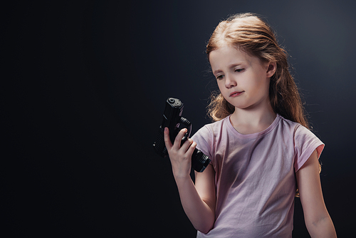 offended child looking at gun in hand on black background