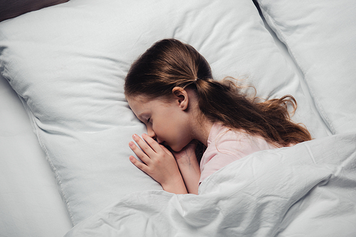 top view of cute child sleeping on white bedding