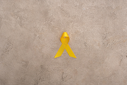 Top view of yellow ribbon on grey background, international childhood cancer day concept