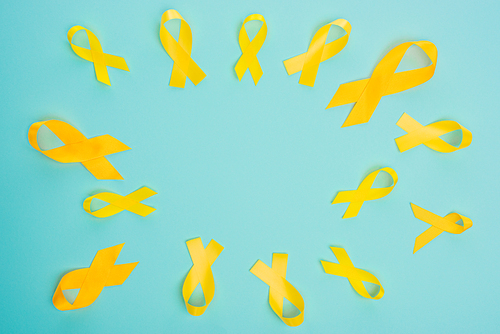 Top view of yellow ribbons on blue background, international childhood cancer day concept