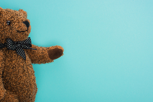 Top view of brown teddy bear with bow on blue background