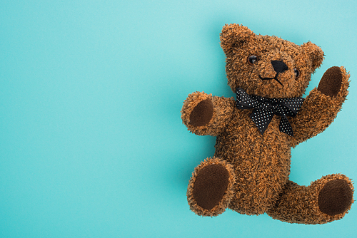 Top view of teddy bear with bow on blue background