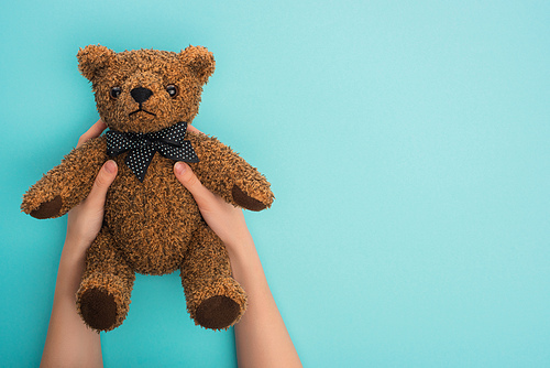 Cropped view of woman holding teddy bear on blue background