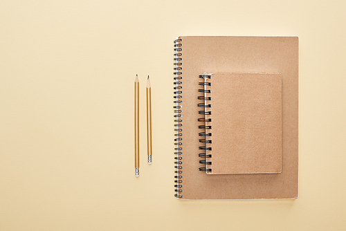 flat lay with paper blank notebooks with pencils on beige background