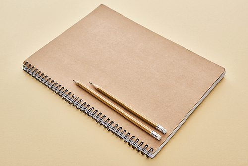 paper blank notebook with pencils on beige background