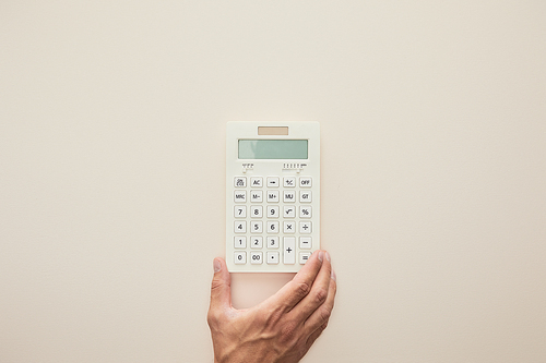 cropped view of man holding calculator isolated on beige