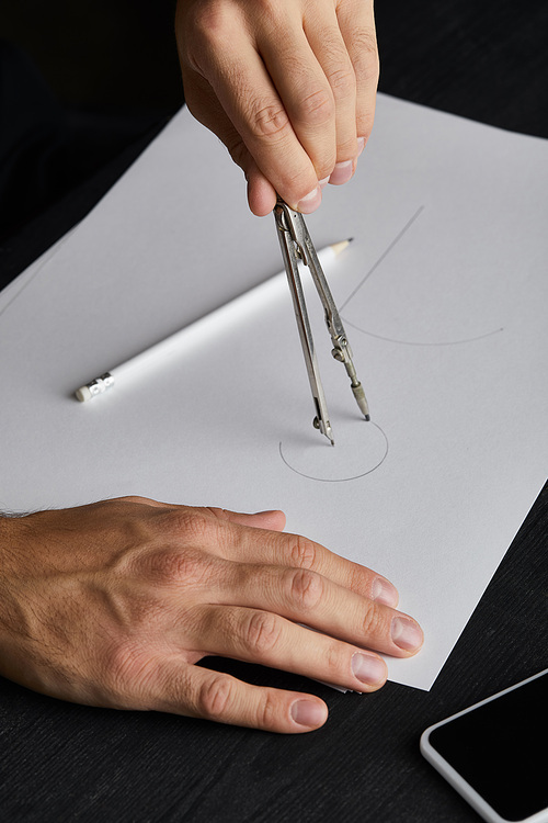 cropped view of man drawing circle on paper with compass