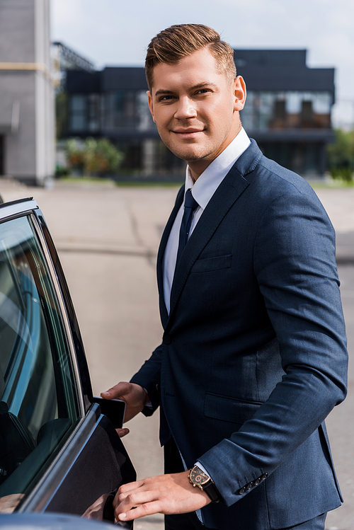 smiling businessman  while opening car door
