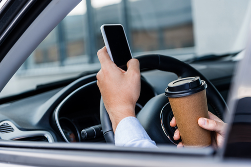 partial view of man holding coffee to go and chatting on smartphone in car on blurred foreground