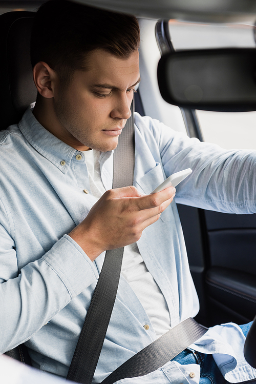 young man messaging on mobile phone while driving car