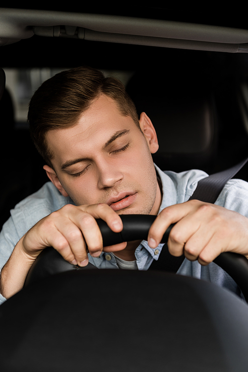 drunk man sleeping at steering wheel in car on blurred foreground