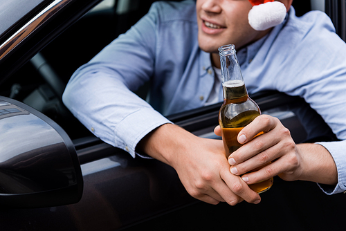 partial view of man looking out car window while holding whiskey, blurred background