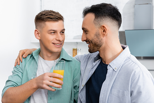 happy man holding glass with orange juice near husband