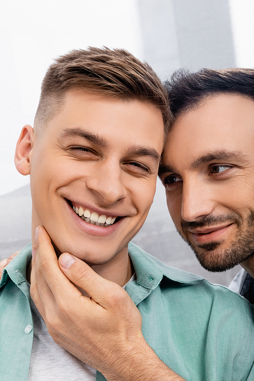 close up of homosexual man touching face of smiling husband at home