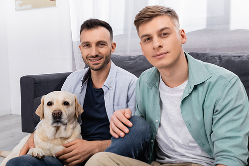 homosexual couple  near labrador in living room
