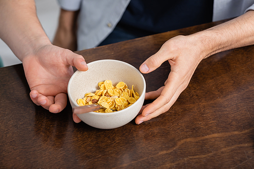 cropped view of homosexual men holding bowl with corn flakes