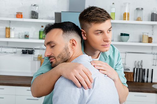 homosexual man calming while hugging worried husband at home