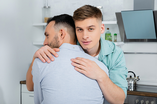 homosexual man calming and hugging worried husband at home