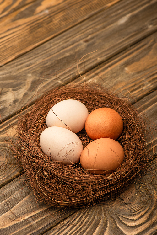 fresh chicken eggs in nest on wooden surface