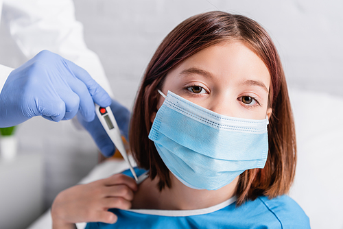 sick girl in medical mask  near doctor with thermometer on blurred background