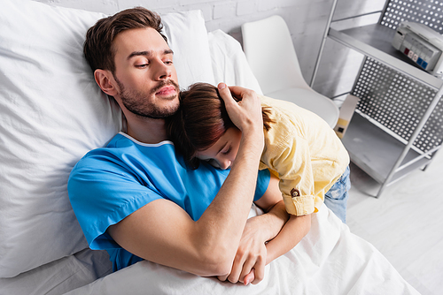 ill man embracing daughter while lying in hospital bed