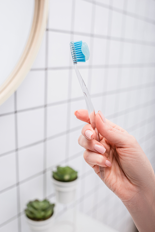 cropped view of woman holding toothbrush in bathroom