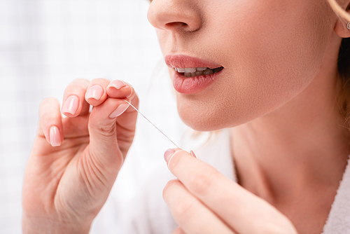 cropped view of woman holding dental floss in bathroom