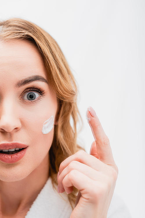 partial view of surprised woman with cosmetic cream on face in bathroom