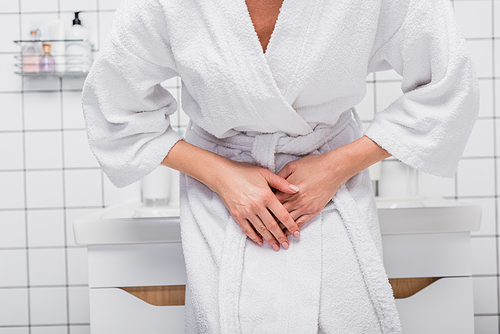 partial view of woman in bathrobe suffering from abdomen pain in bathroom