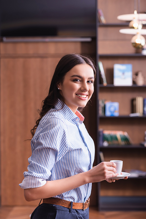 cheerful young businesswoman  while holding cup of coffee in restaurant