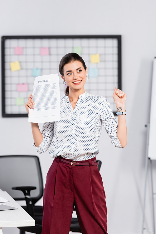 happy businesswoman holding contract in office