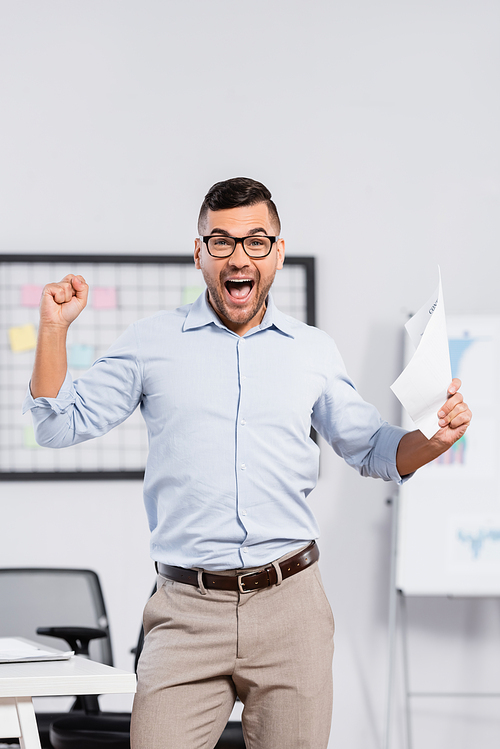 excited businessman in glasses holding document in office