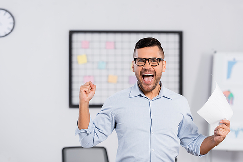 amazed businessman with open mouth holding paper in office