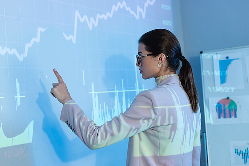 businesswoman in glasses and pointing with finger at digital graphs
