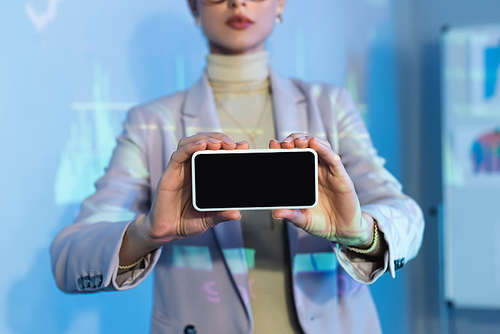partial view of businesswoman holding smartphone with blank screen