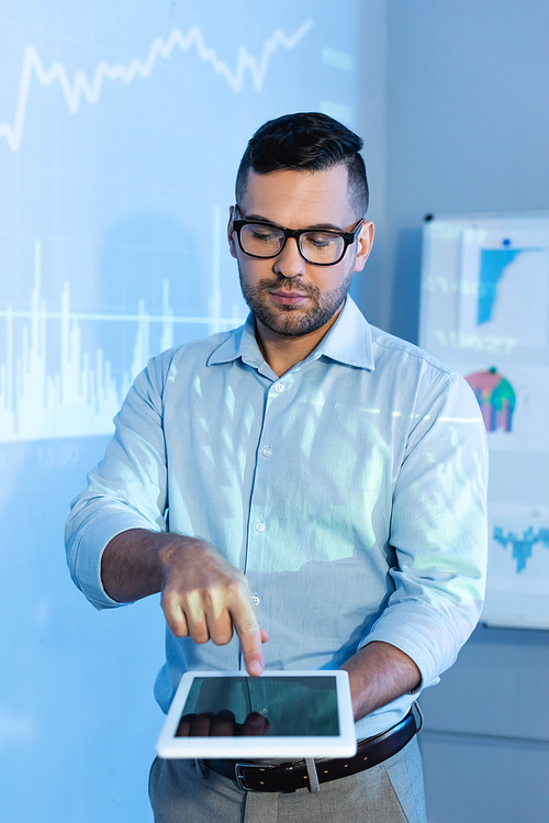 businessman in glasses pointing with finger at digital tablet with blank screen