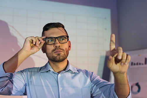 businessman in glasses pointing with finger on blurred foreground