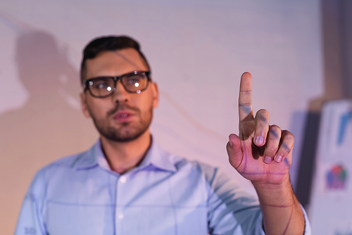 blurred businessman in glasses pointing with finger in office