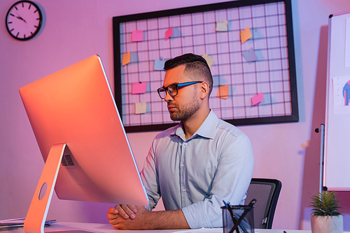 businessman in glasses looking at computer monitor in office