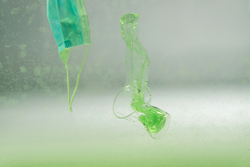 medical mask, plastic bag and cup underwater, ecology concept