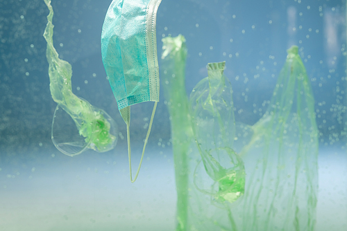 plastic bags and cups near medical mask underwater, ecology concept