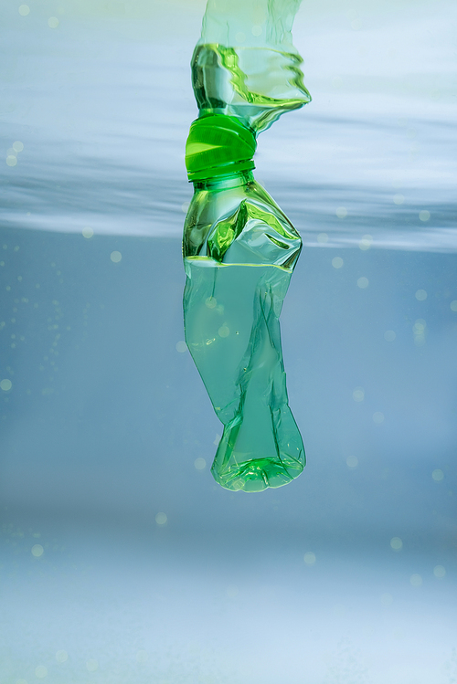 crumpled plastic bottle in water, ecology concept