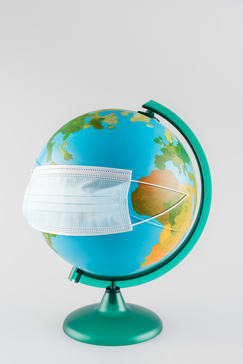 protective mask on earth globe isolated on grey, ecology concept