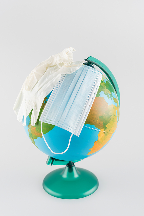 medical mask and latex gloves on globe isolated on grey, ecology concept