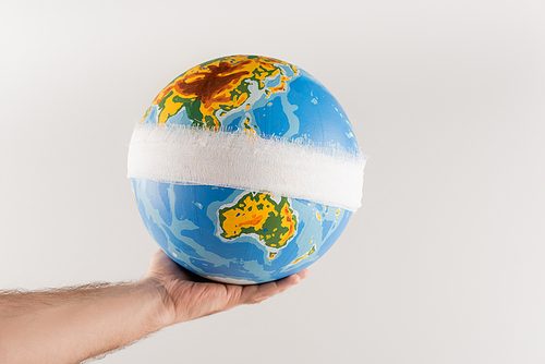 partial view of man holding bandaged globe isolated on grey, ecology concept