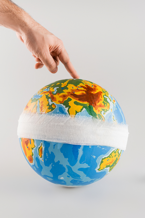 cropped view of man touching bandaged globe on grey, ecology concept