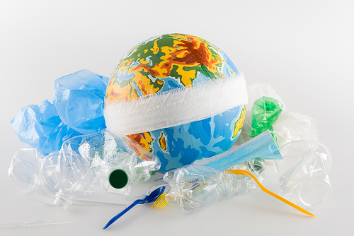 bandaged globe near plastic garbage on grey, ecology concept