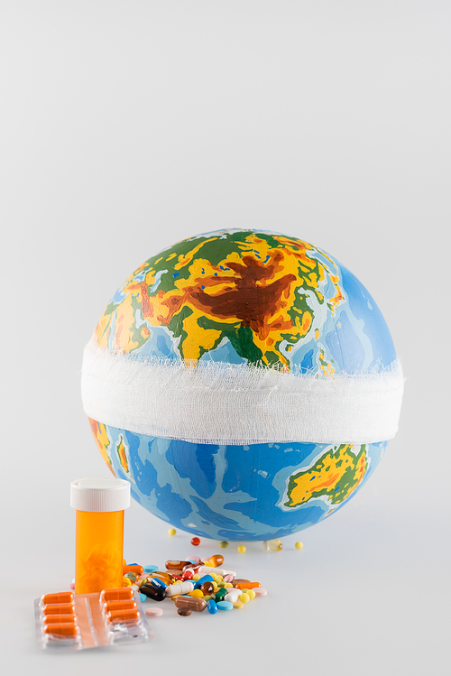 bandaged globe near pills on grey background, ecology concept