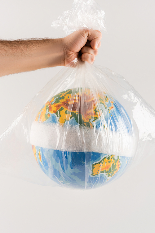 partial view of man holding plastic bag with bandaged globe isolated on grey, ecology concept